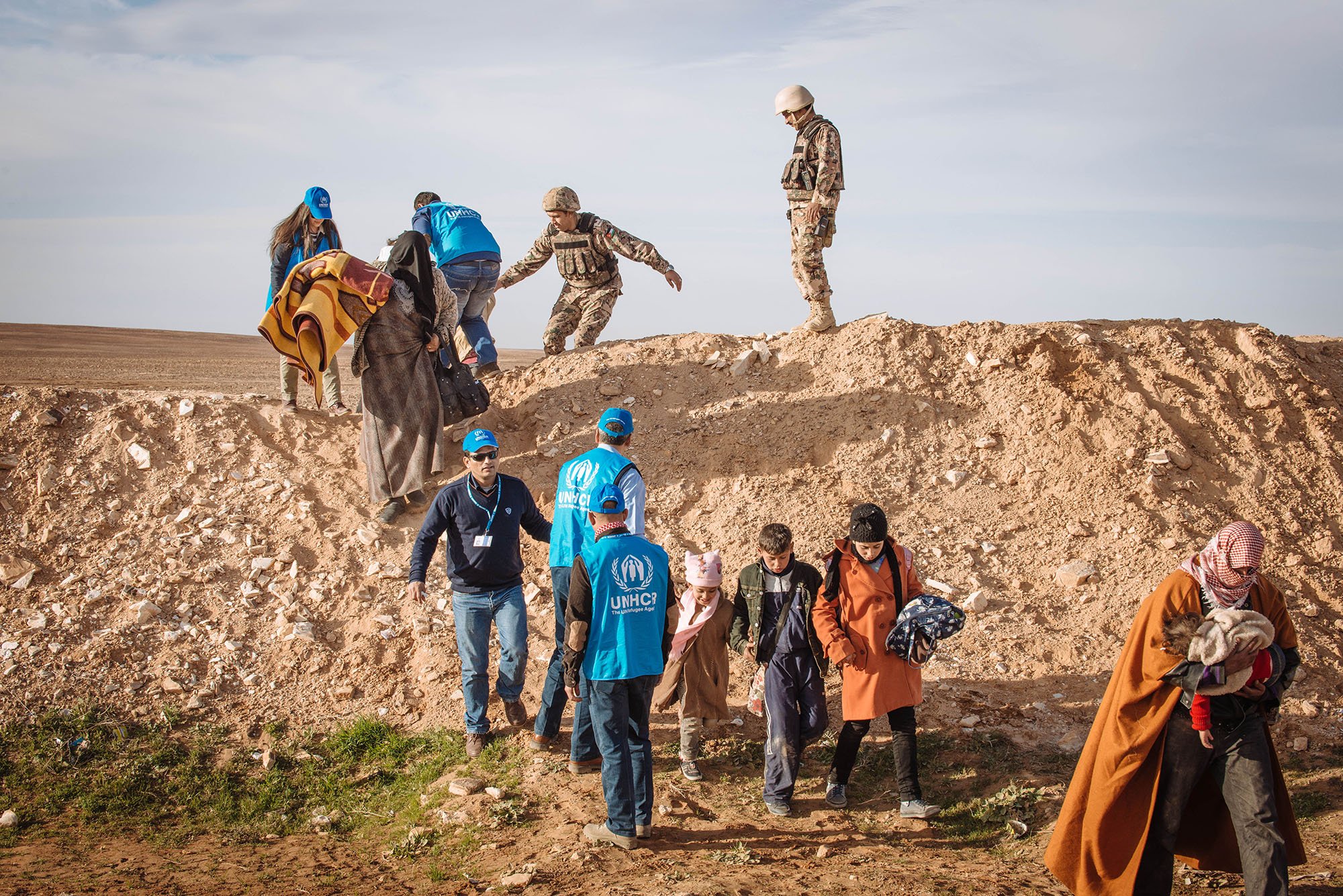 Syrian refugees walk the final metres across the desert toward 'the Berm' that marks the official Al-Ruwayshid Jordanian / Syrian border crossing. Photo: UNCHR / J. Kohler