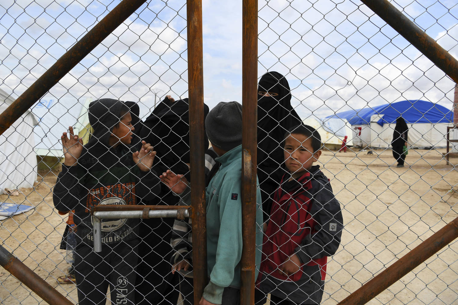 Wives and children of former ISIS fighters gather at the fence in the foreign section of the al-Hawl refugee camp in northern Syria, waiting to be taken to the camp shops, April 2, 2019. . Photo:  Kate Geraghty/Getty Images