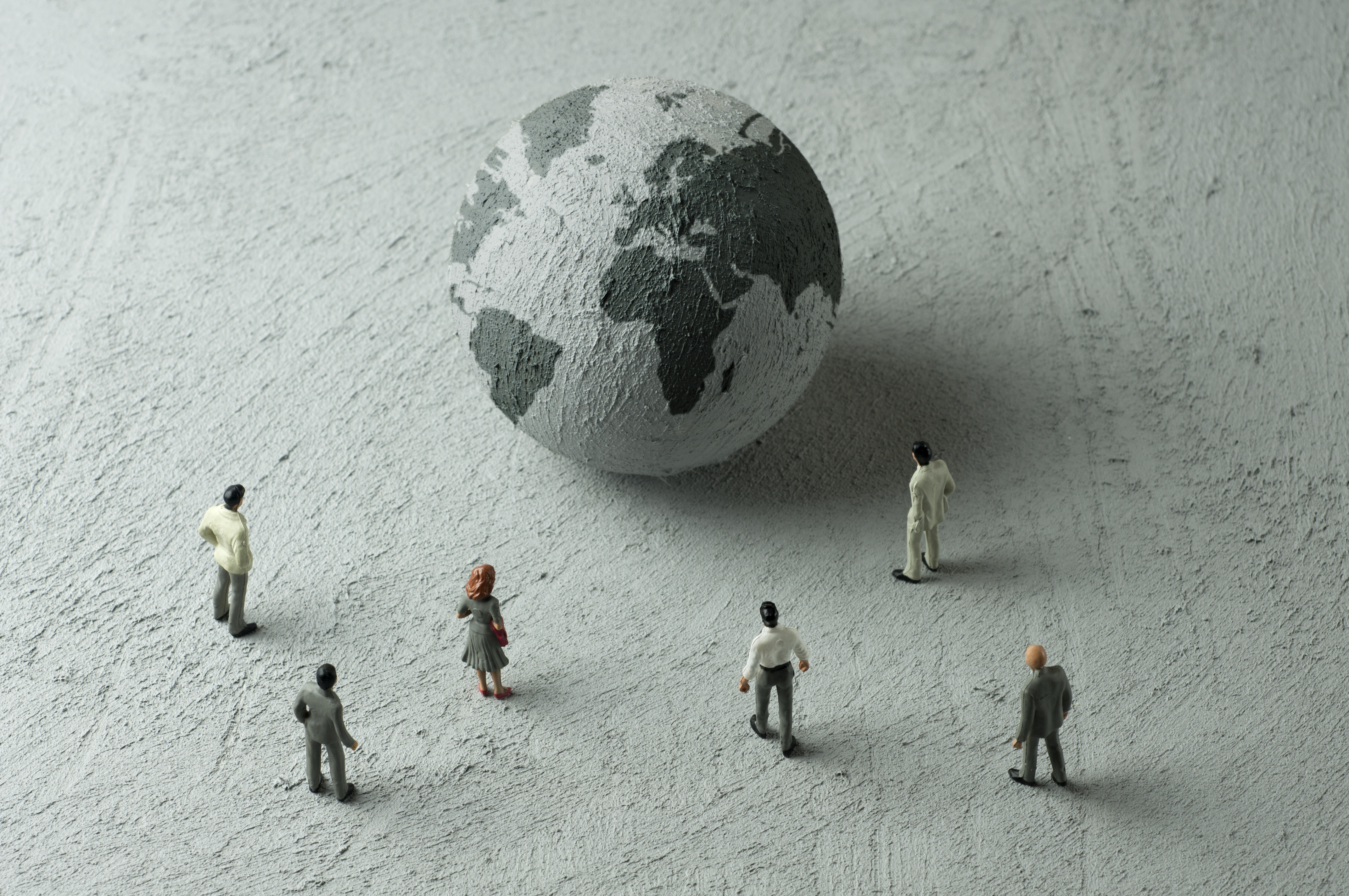 Politician figurines examine a concrete globe. Illustration: Hamza Turkkol