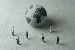 Politician figurines examine a concrete globe. Illustration: Hamza Turkkol