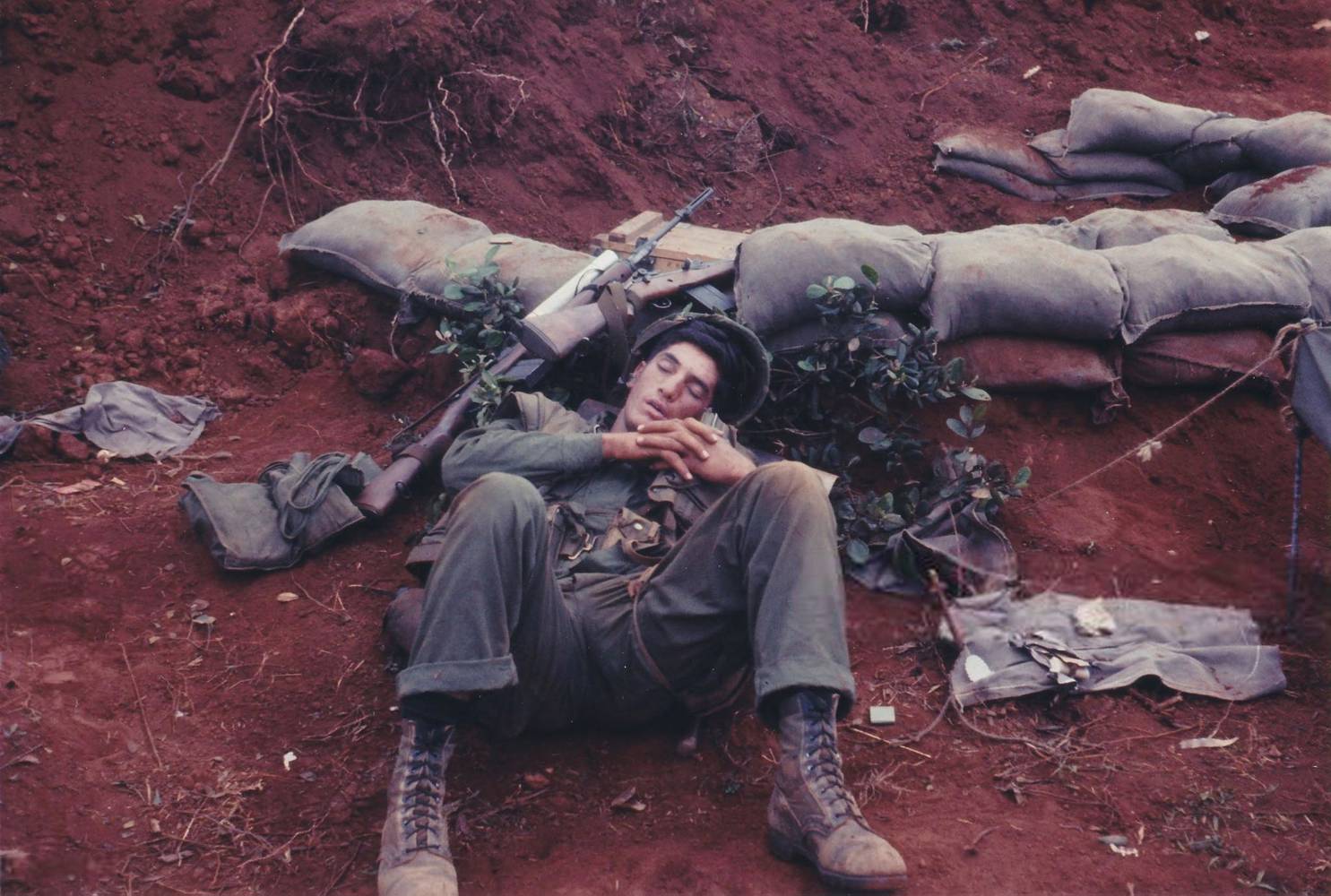 Slightly high-angle shot of an American serviceman, lying asleep in the dirt near a ring of sandbags, with his rifle resting near his head, Vietnam, 1965. (Photo by Stuart Lutz/Gado/Getty Images). Photo: Stuart Lutz/Gado / CCBY 2.0 / Flickr