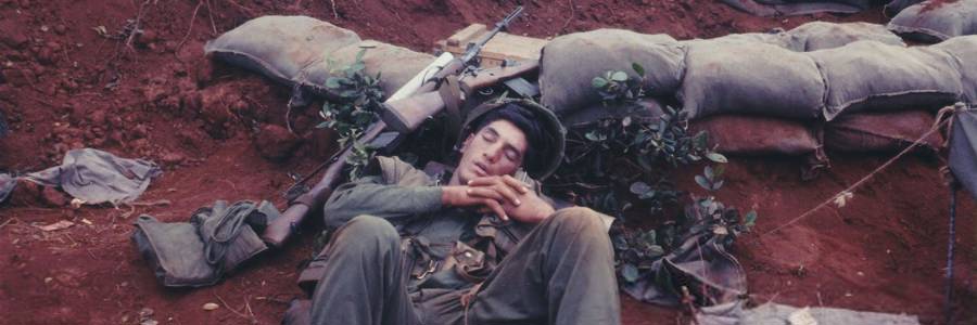 Slightly high-angle shot of an American serviceman, lying asleep in the dirt near a ring of sandbags, with his rifle resting near his head, Vietnam, 1965. (Photo by Stuart Lutz/Gado/Getty Images). Photo: Stuart Lutz/Gado / CCBY 2.0 / Flickr