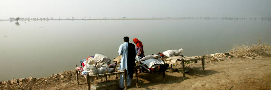 A family setting up 'charpoy' beds next to a vast expanse of flooded fields in Pakistan's Sindh Province - the land that they used to farm. Photo: Russell Watkins / UK Department for International Development