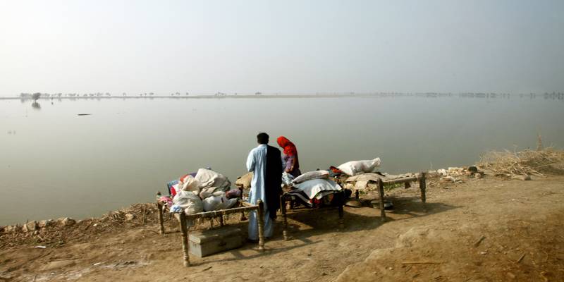 A family setting up 'charpoy' beds next to a vast expanse of flooded fields in Pakistan's Sindh Province - the land that they used to farm. Russell Watkins / UK Department for International Development