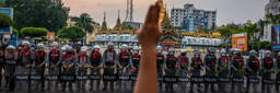 A protester makes a three-finger salute in front of a row of riot police, who are holding roses given to them by protesters, on February 06, 2021 in Yangon, Myanmar. . Photo: Stringer/Getty Images