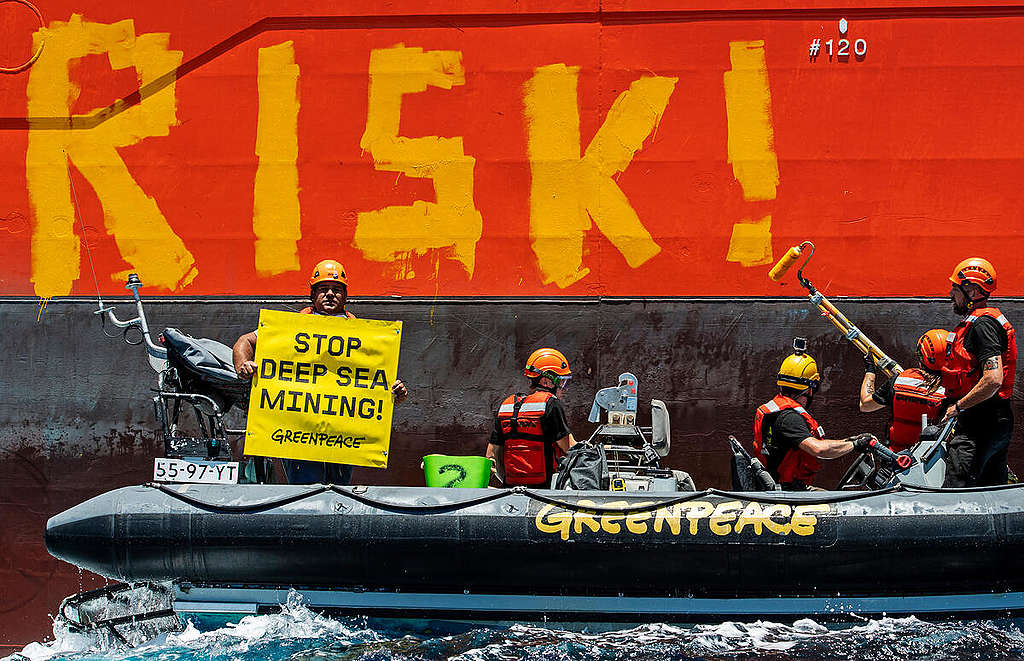 Greenpeace activists paint the word ‘RISK!’ on the side of a vessel chartered by the company Global Sea Mineral Resources (GSR). Photo: Marten van Dijl / Greenpeace