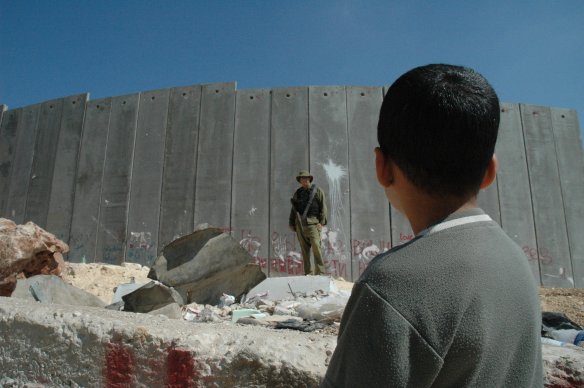 Palestinian boy and Israeli soldier in front of the West Bank barrier. Photo: CC BY 2.0
