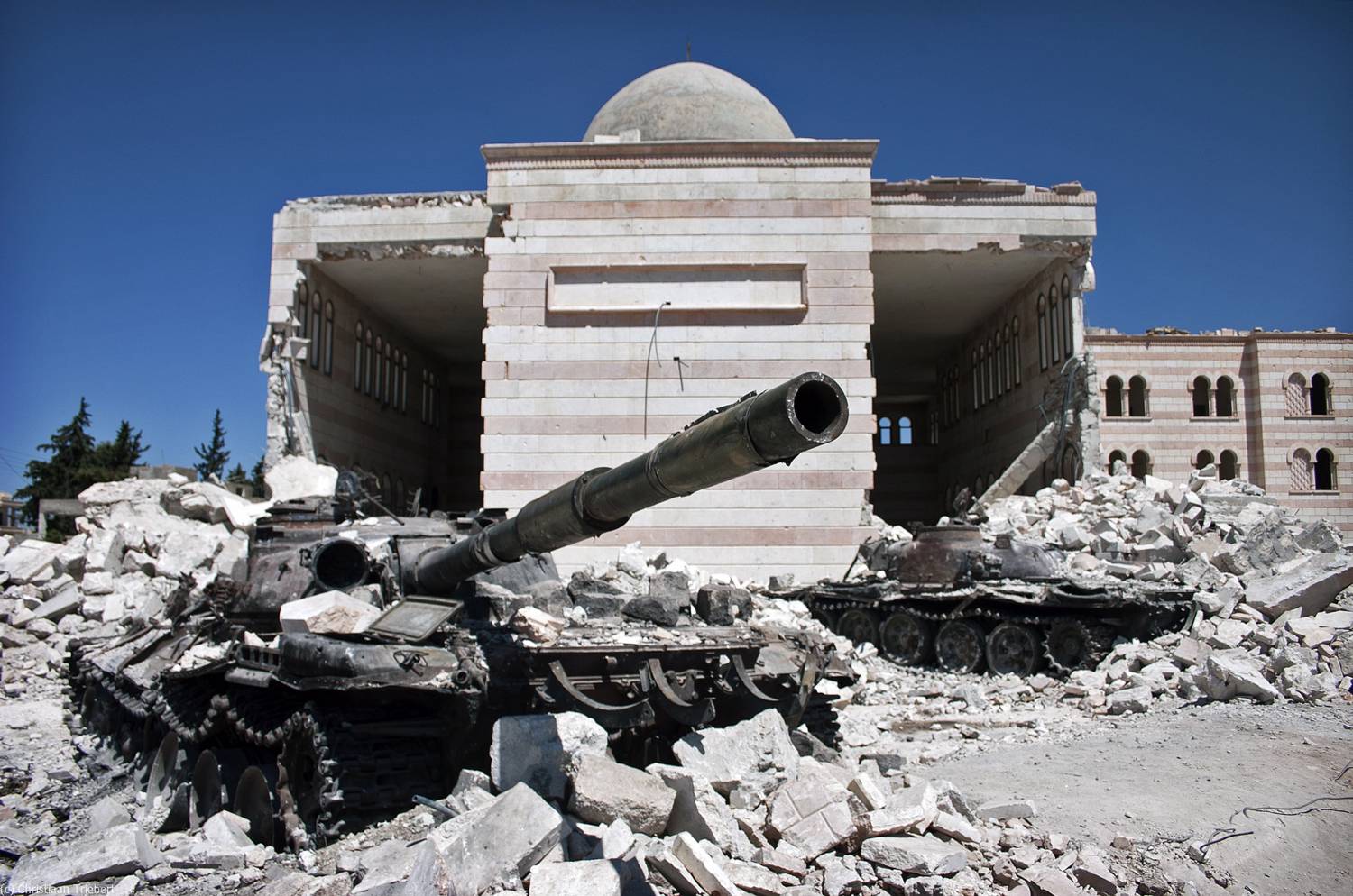 Destroyed tanks in front of a mosque in Azaz, Syria. From March 6 to July 23, a battle between the Free Syrian Army (FSA) and the Syrian Arab Army (SAA) was fought for control over the city of Azaz, north of Aleppo, during the Syrian civil war. Christiaan Triebert / Flickr