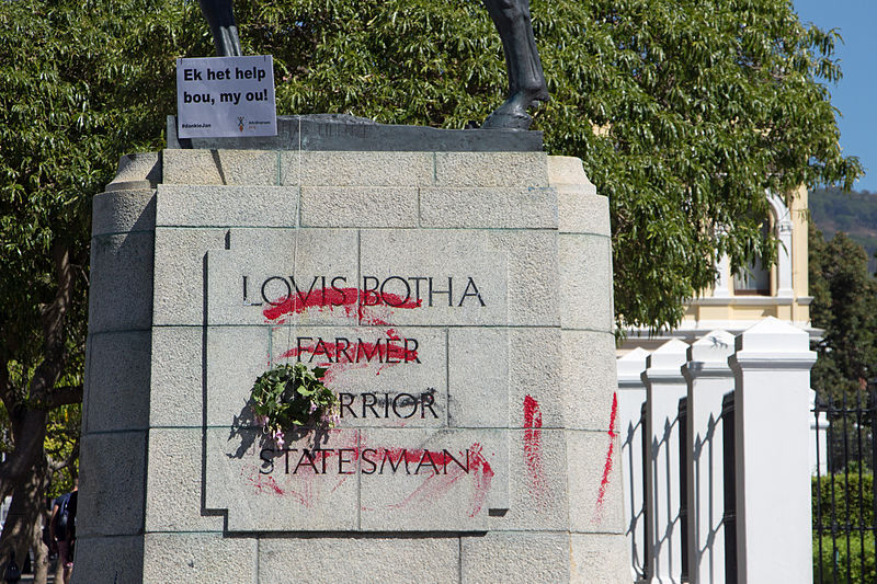 Defaced statue of Louis Botha outside the Houses of Parliament in Cape Town during the Rhodes Must Fall campaign. The wreaths were placed on the defaced statue by members of AfriForum. The AfriForum sign says Ek het help bou, ou! ('I helped build, friend!') and #dankieJan ('#thanksJan'). Wikimedia Commons