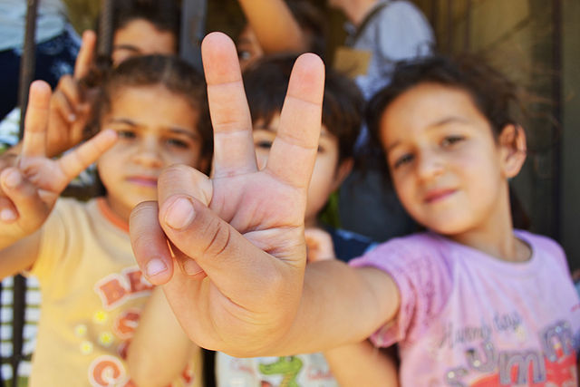 Syrian refugee children in Lebanon, give the peace sign (Photo: Eoghan Rice)- Creative Commons Attribution 2.0 Generic.
