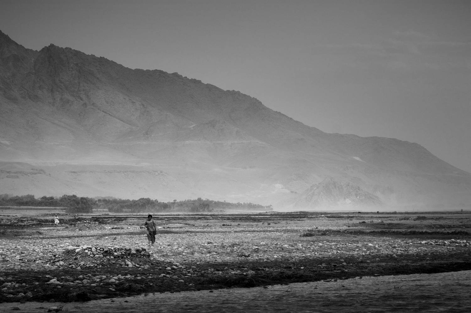 BAGRAM AIR FIELD, Afghanistan -- Two local Afghans walk across a river valley in Mahmood Raqi District, Kapisa Province, Afghanistan, September 16, 2008. Photo: (U.S. Air Force photo by Staff Sgt. Samuel Morse/Released)