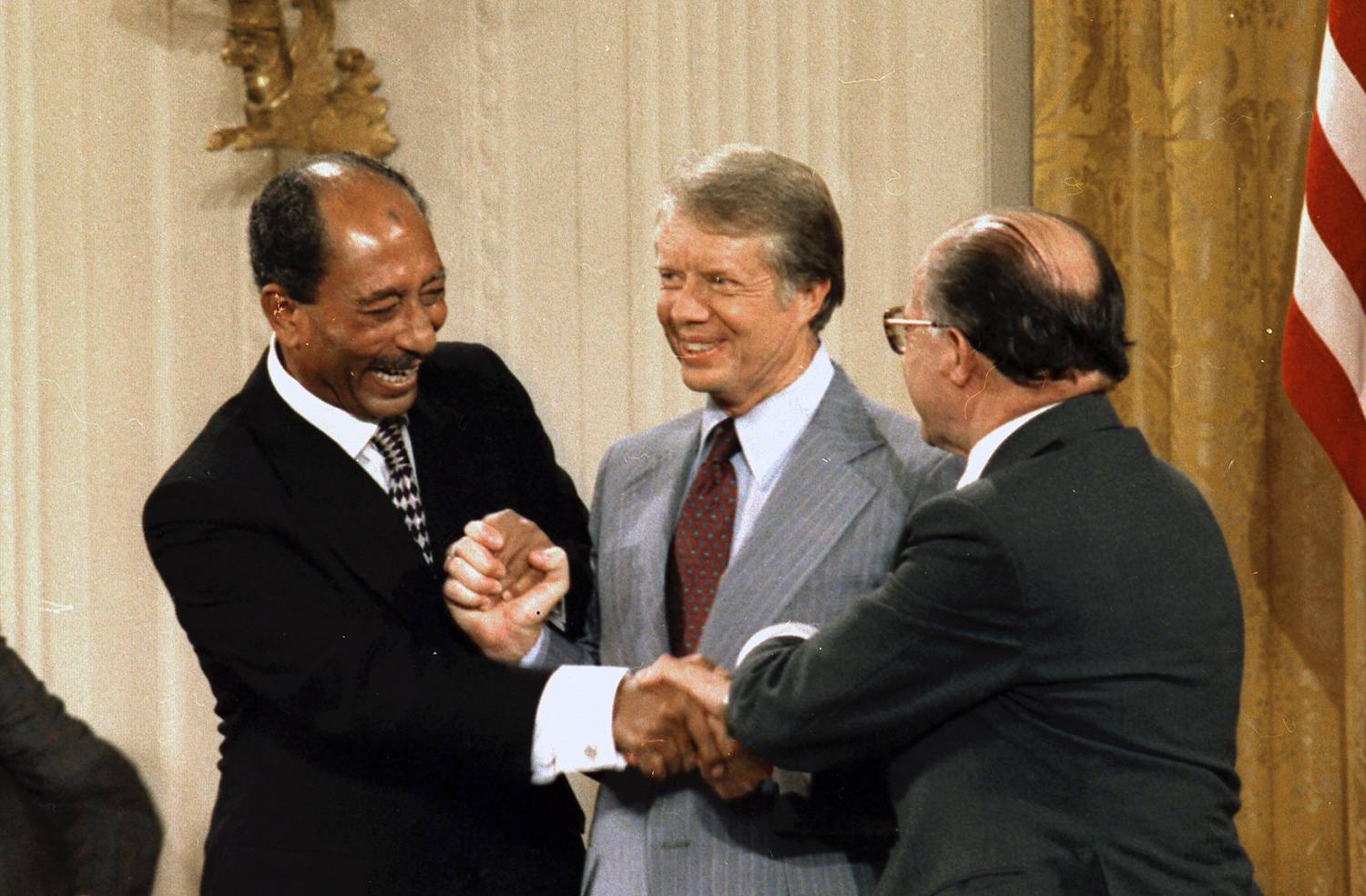 Egyptian President Anwar Sadat, U.S. President Jimmy Carter, and Israeli Prime Minister Menachem Begin shake hands at the conclusion of the Camp David Peace Accords signing ceremony. US National Archives and Records Administration CC