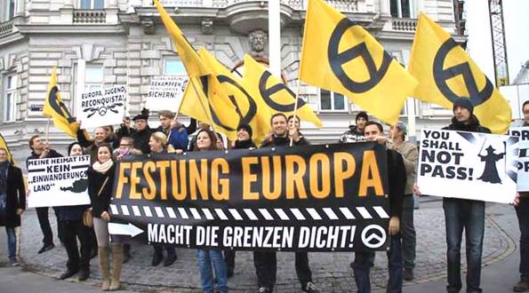 Far-right activists at an Identitarian Movement of Austria anti-immigration rally in Vienna. The German-language signs read 'Fortress Europe', 'Close the Borders Now!', 'My Home is Not an Immigrant Country', and 'Europe, Youth, Reconquista'. Photo: Wikimedia Commons