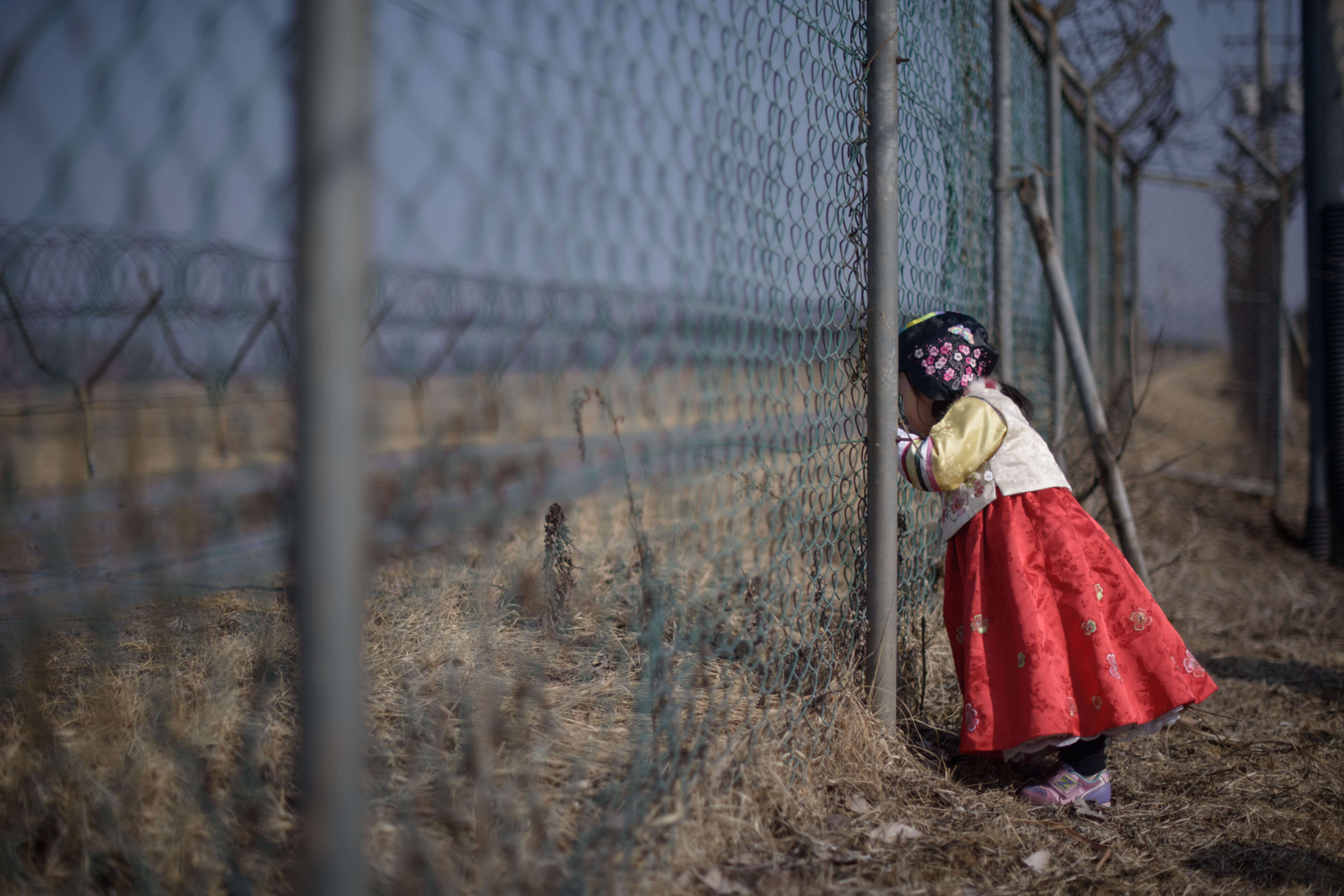 A girl wearing a traditional hanbok dress stands at a military fence facing towards North Korea at Imjingak park, south of the Military Demarcation Line and Demilitarized Zone (DMZ) separating North and South Korea, on February 19, 2015. Photo: ED JONES / Afp / NTB